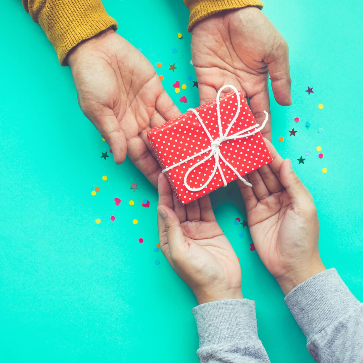 A pair of hands giving a wrapped gift to another pair of hands