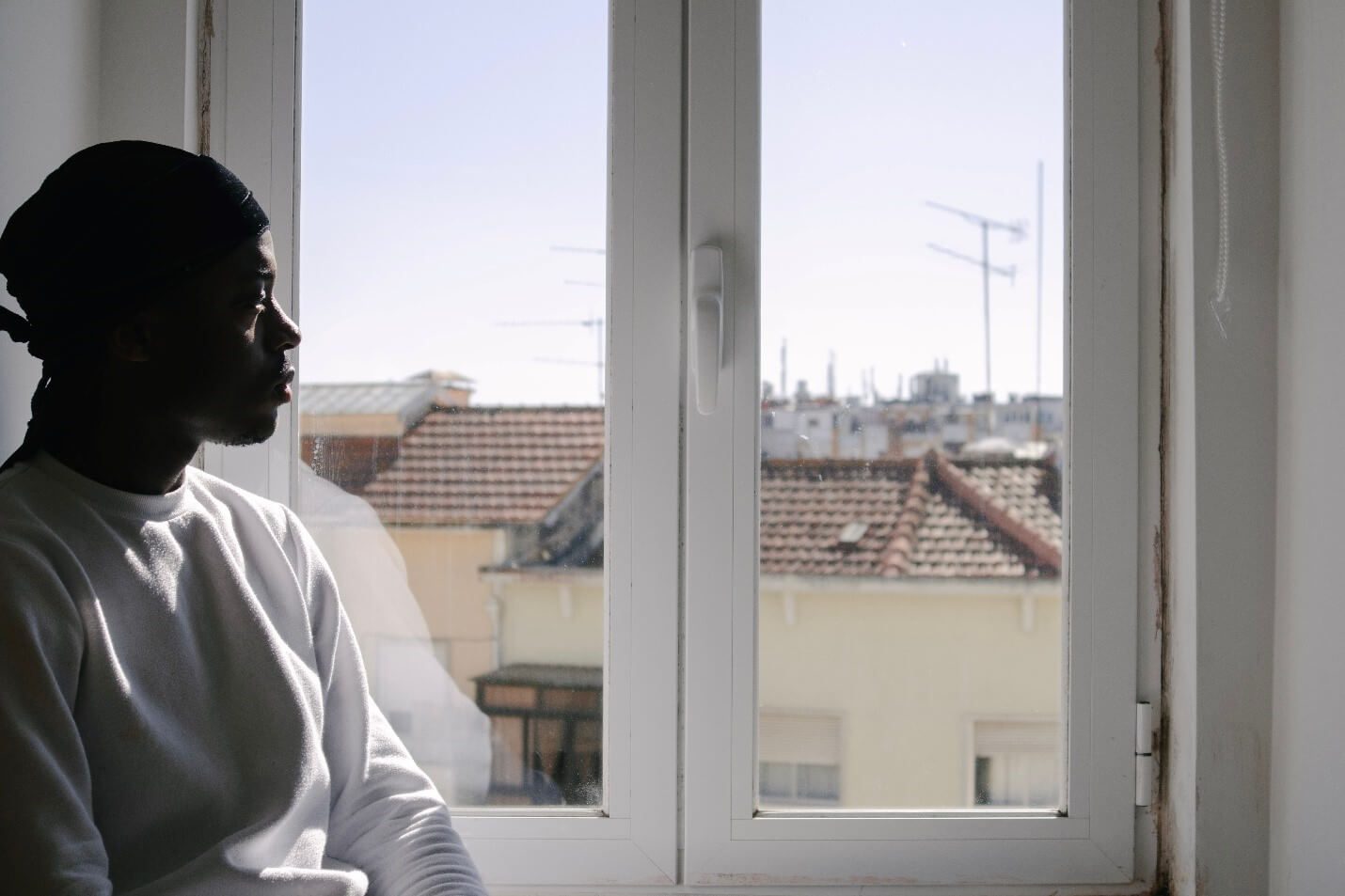 A Black man stares out a window.